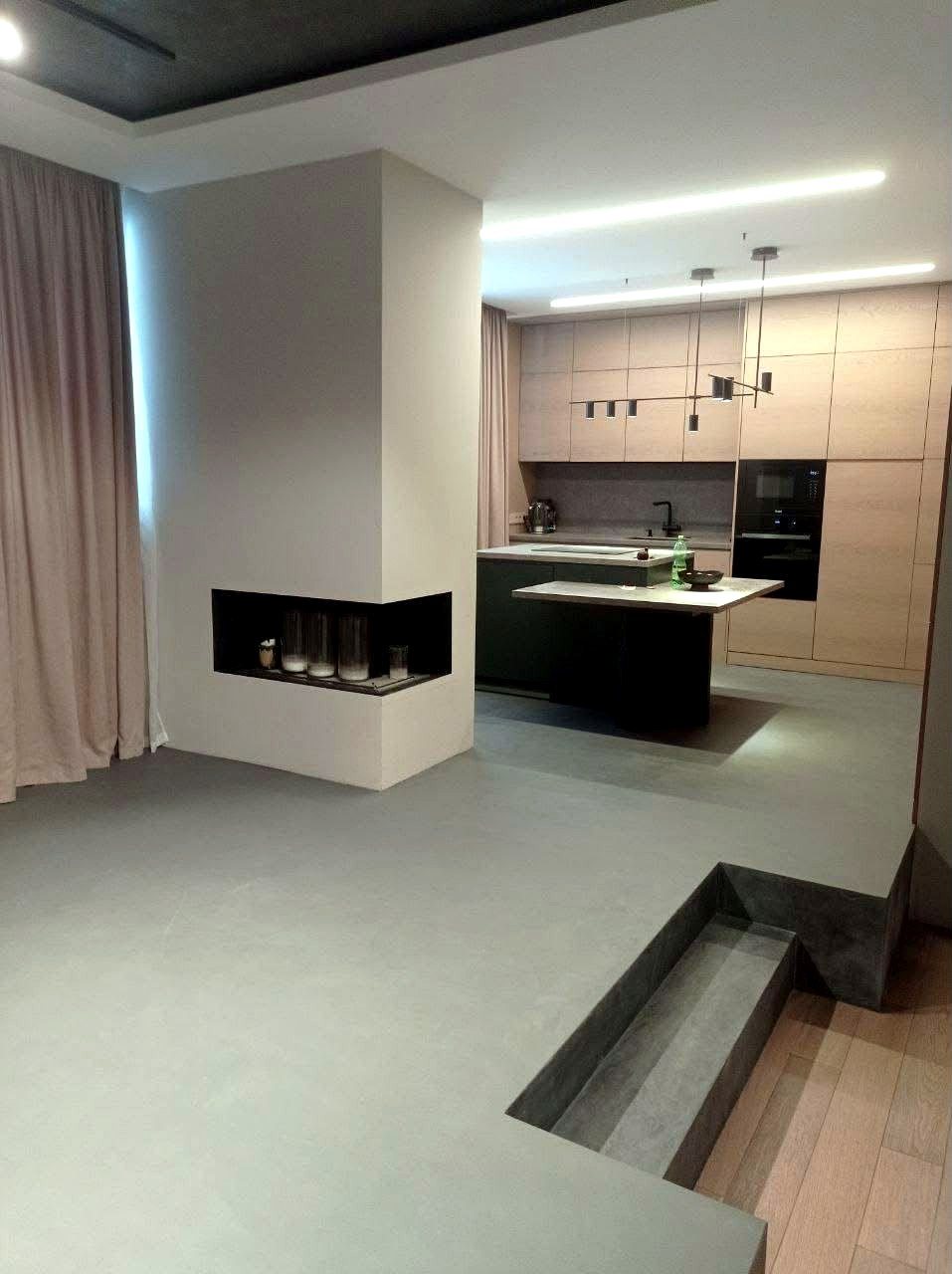 Open-plan kitchen with a seamless microcement floor running past the fireplace