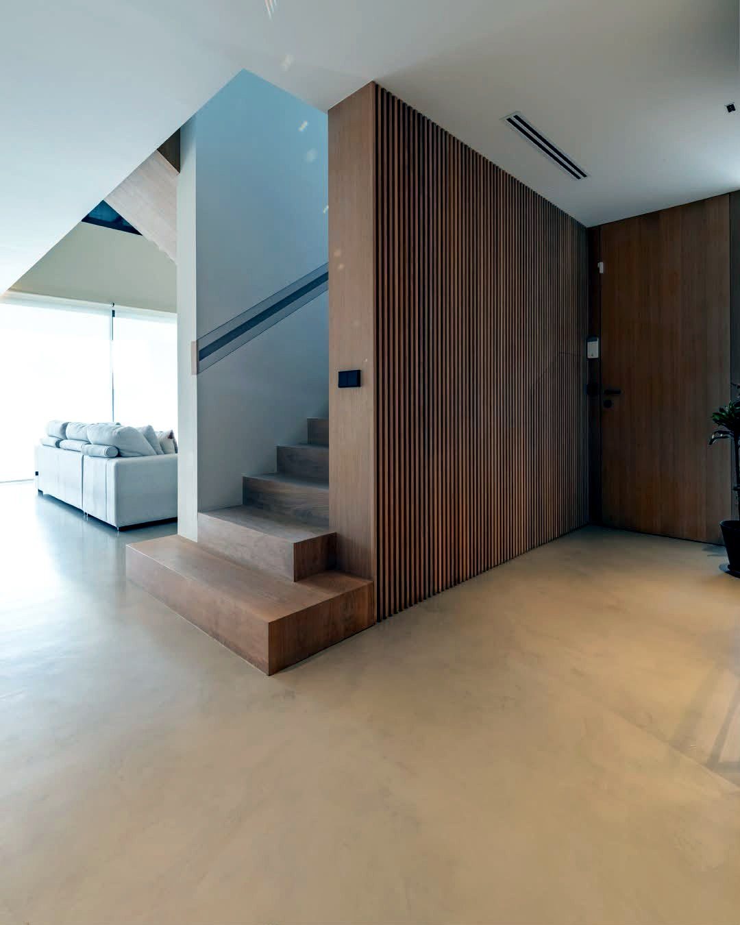Hallway and staircase finished in pale microcement running through into the living room with no thresholds