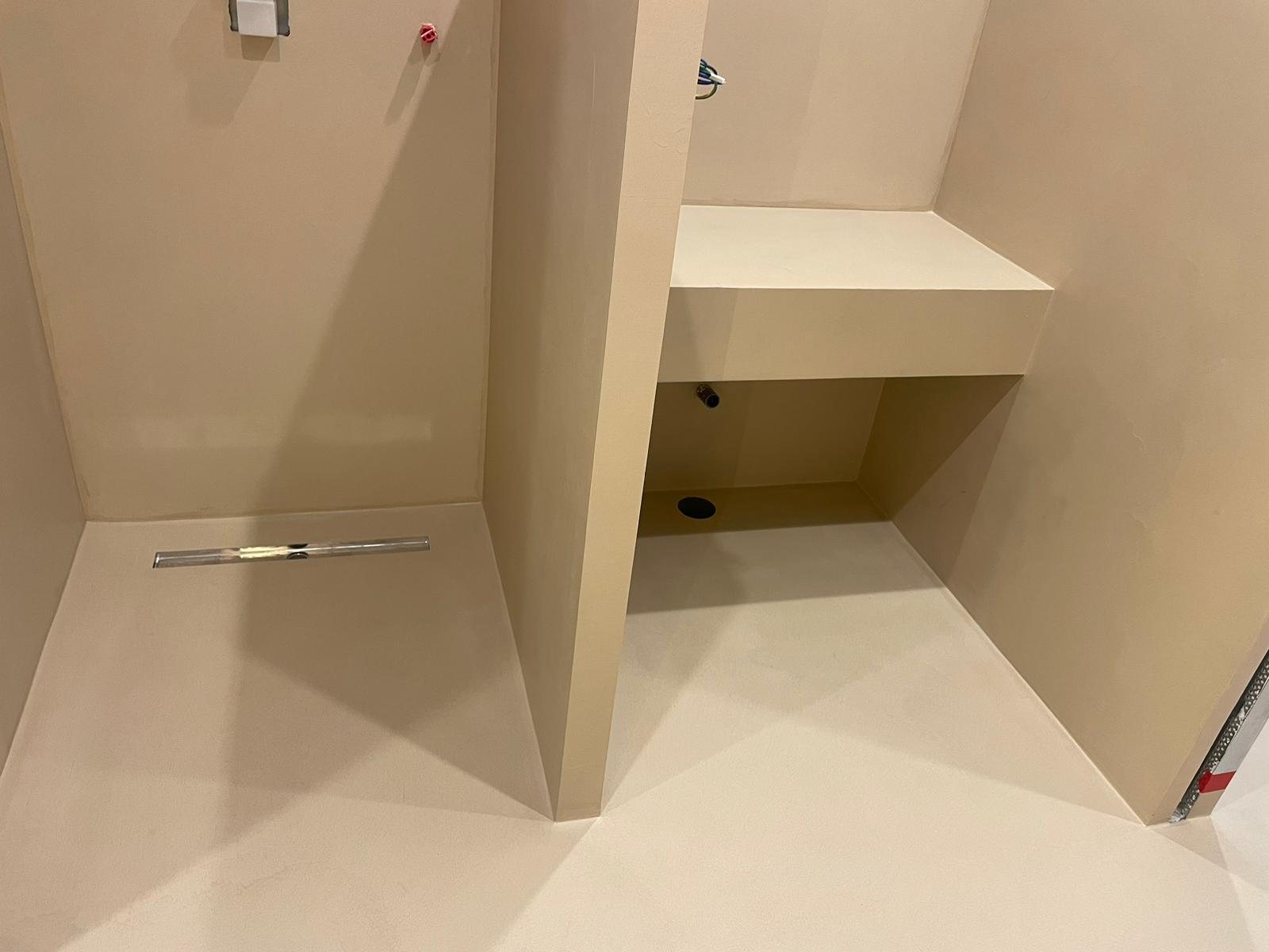Real shower installation with microcement niche and linear drain, warm camel tone, fitted by our team